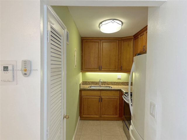 900 NE 18th Ave Unit 304, Fort Lauderdale, FL 33304 - kitchen featuring stainless steel electric range oven, brown cabinets, light tile patterned floors, and freestanding refrigerator