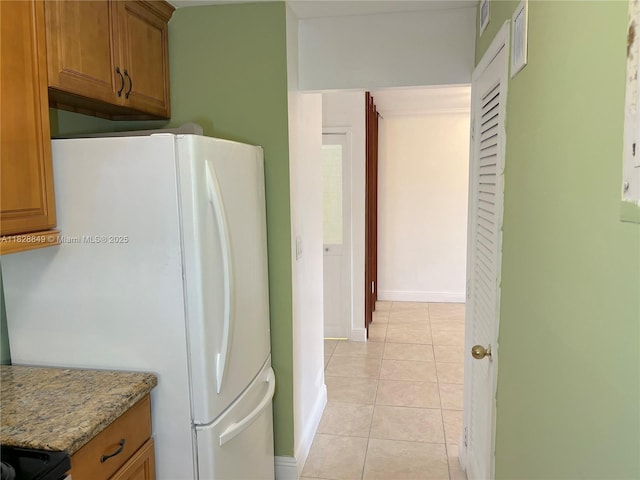 900 NE 18th Ave Unit 304, Fort Lauderdale, FL 33304 - kitchen featuring freestanding refrigerator, brown cabinetry, and light tile patterned flooring