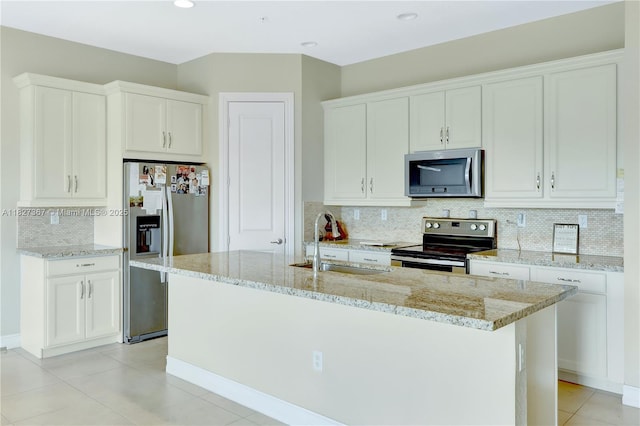1601 SW 113th Ave, Pembroke Pines, FL 33025 - kitchen with appliances with stainless steel finishes, decorative backsplash, white cabinetry, light stone countertops, and a kitchen island with sink