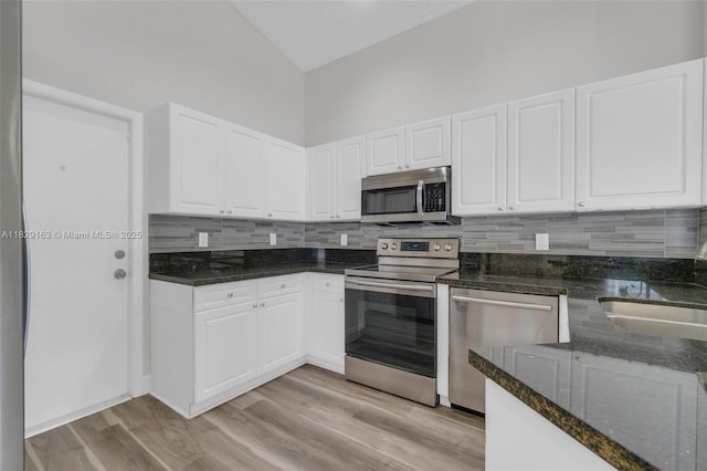 1592 Salerno Cir, Weston, FL 33327 - kitchen with appliances with stainless steel finishes, dark stone counters, backsplash, white cabinets, and light wood finished floors