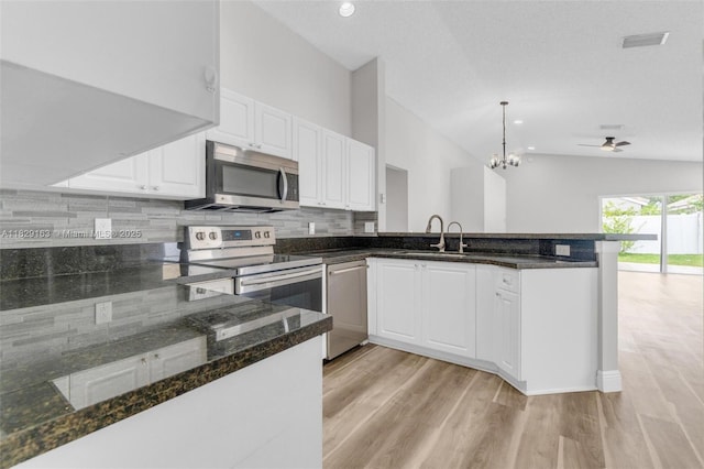 1592 Salerno Cir, Weston, FL 33327 - kitchen featuring stainless steel appliances, a peninsula, lofted ceiling, light wood finished floors, and tasteful backsplash