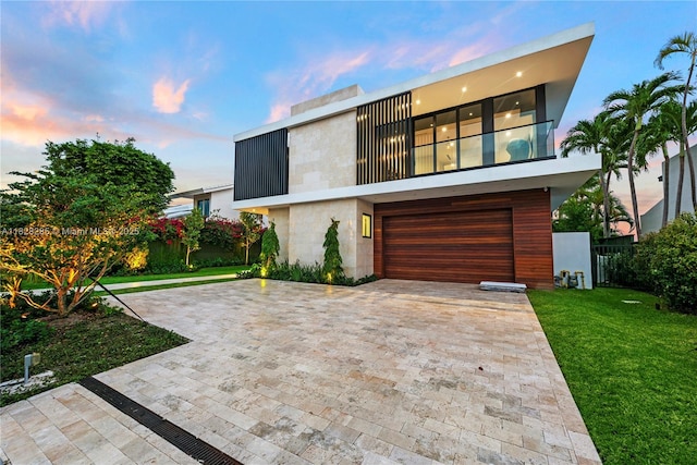 1410 S Biscayne Point Rd, Miami Beach, FL 33141 - modern home featuring decorative driveway, an attached garage, a front lawn, and a balcony