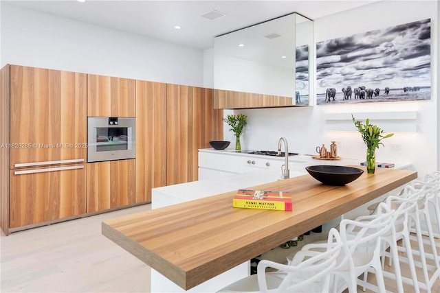 1410 S Biscayne Point Rd, Miami Beach, FL 33141 - kitchen featuring light countertops, a peninsula, light wood-type flooring, brown cabinets, and modern cabinets