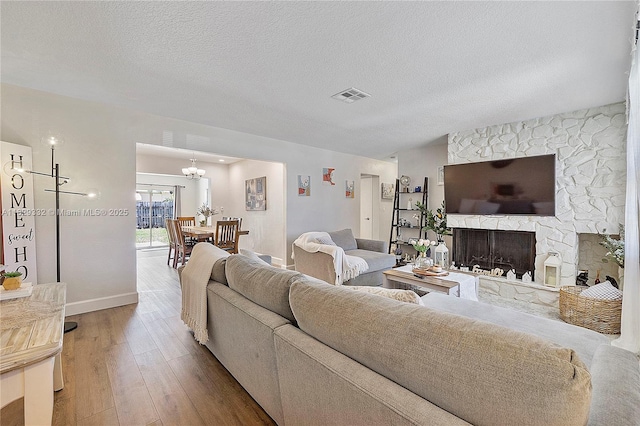 3301 NW 42nd St, Lauderdale Lakes, FL 33309 - living area featuring wood-type flooring, a stone fireplace, a chandelier, and a textured ceiling
