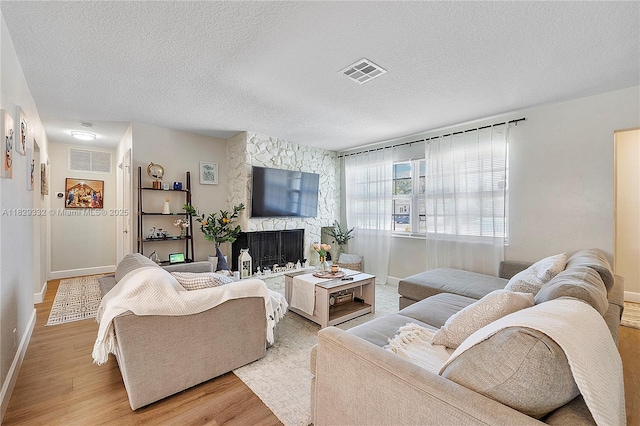 3301 NW 42nd St, Lauderdale Lakes, FL 33309 - living room with light wood-style floors, a textured ceiling, and a stone fireplace