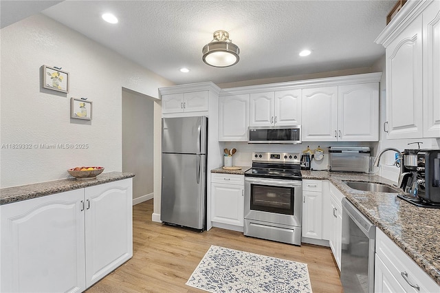 3301 NW 42nd St, Lauderdale Lakes, FL 33309 - kitchen featuring appliances with stainless steel finishes, stone counters, white cabinetry, a textured ceiling, and light wood-type flooring