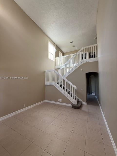 3736 SW 50th St, Hollywood, FL 33312 - unfurnished living room with tile patterned flooring, arched walkways, stairs, and a textured ceiling