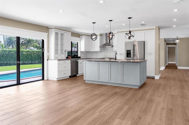 9745 SW 126th Ter, Miami, FL 33176 - kitchen with stainless steel appliances, wall chimney exhaust hood, tasteful backsplash, light wood finished floors, and a kitchen island with sink