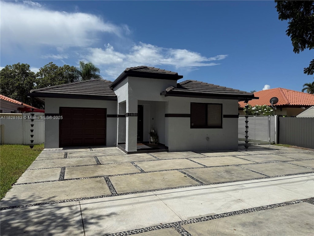 14480 SW 112th St, Miami, FL 33186 - prairie-style house featuring stucco siding, driveway, an attached garage, and a tiled roof