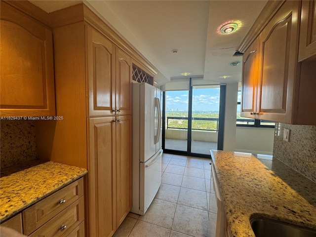 2555 Collins Ave Unit 2002, Miami Beach, FL 33140 - kitchen with freestanding refrigerator, decorative backsplash, light stone counters, and a wall of windows