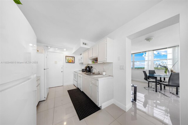 3161 S Ocean Dr Unit 1510, Hallandale Beach, FL 33009 - kitchen with light countertops, white cabinets, track lighting, white appliances, and light tile patterned floors