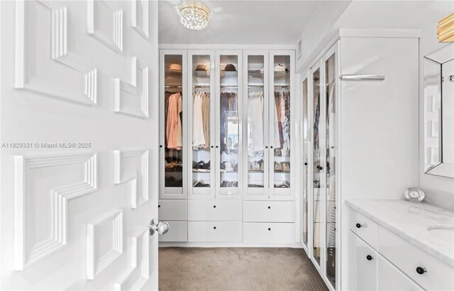 900 Bay Dr Unit 702/704, Miami Beach, FL 33141 - spacious closet featuring carpet floors and a chandelier