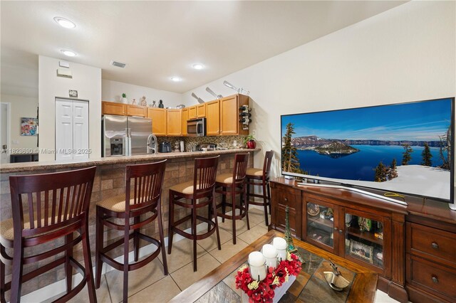 448 SE 32nd Ave, Homestead, FL 33033 - kitchen with stainless steel appliances, light tile patterned flooring, decorative backsplash, a breakfast bar area, and a peninsula