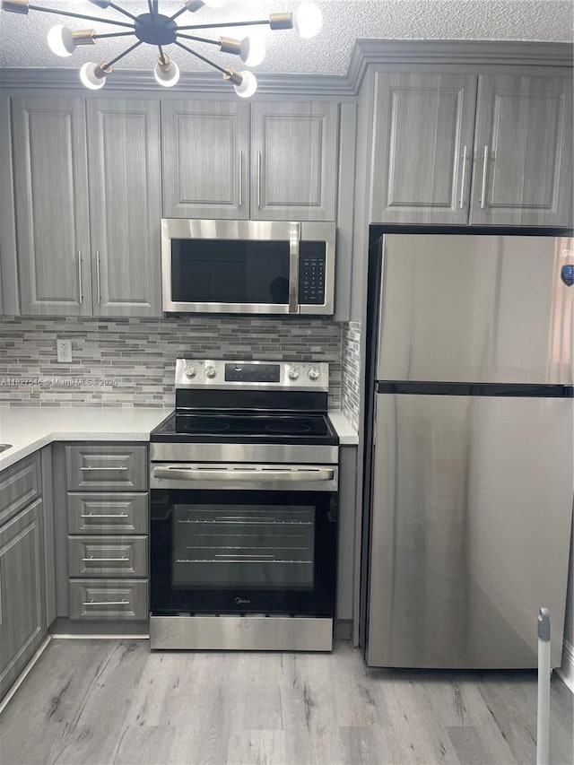 365 NE 125th St Unit 302, North Miami, FL 33161 - kitchen featuring appliances with stainless steel finishes, gray cabinetry, a chandelier, light countertops, and tasteful backsplash