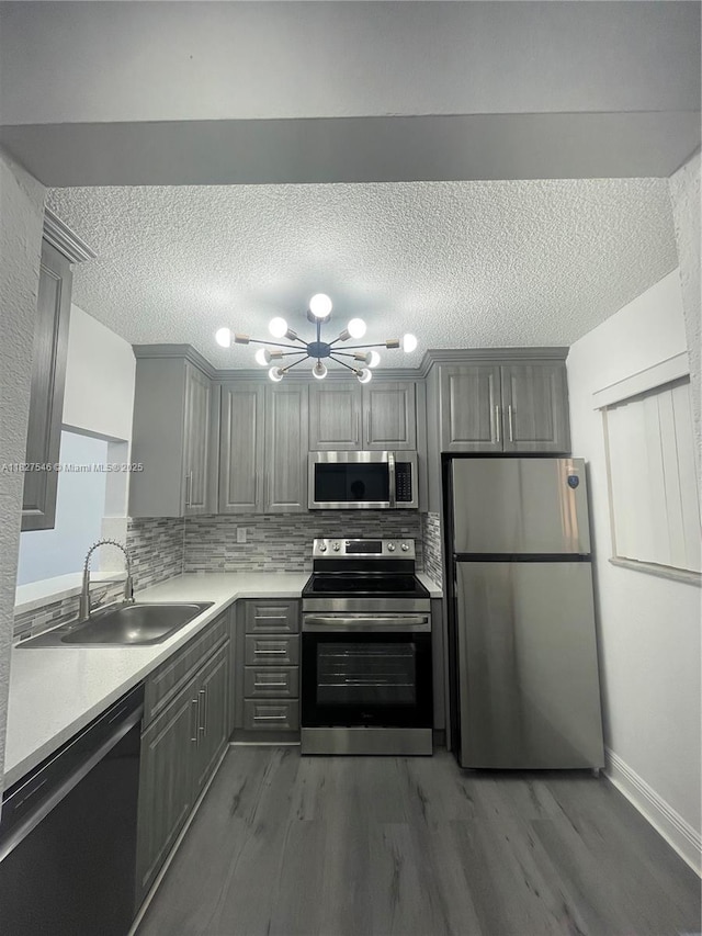365 NE 125th St Unit 302, North Miami, FL 33161 - kitchen featuring stainless steel appliances, gray cabinetry, a chandelier, wood finished floors, and a textured ceiling