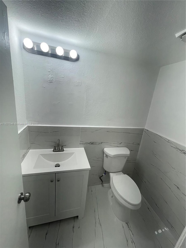 365 NE 125th St Unit 302, North Miami, FL 33161 - half bath with marble finish floors, vanity, a textured ceiling, a wainscoted wall, and tile walls