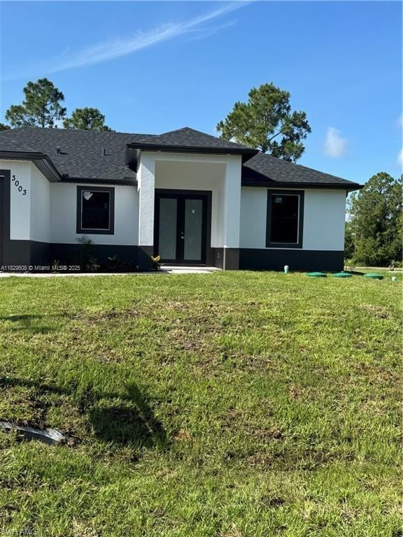 3003 18th St W, Lehigh Acres, FL 33976 - view of front facade with stucco siding, a front lawn, and french doors