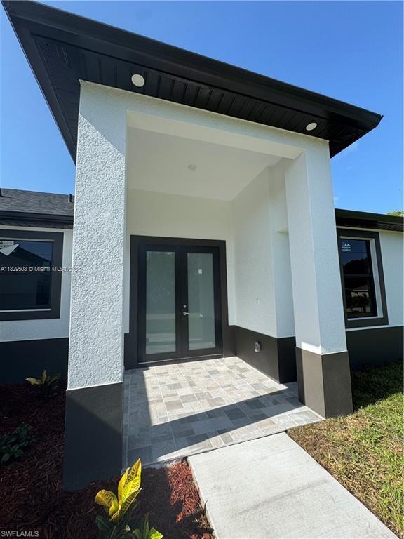 3003 18th St W, Lehigh Acres, FL 33976 - view of exterior entry featuring stucco siding and french doors