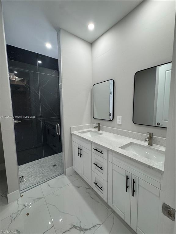 3003 18th St W, Lehigh Acres, FL 33976 - bathroom featuring double vanity, a marble finish shower, marble look tiles, and recessed lighting