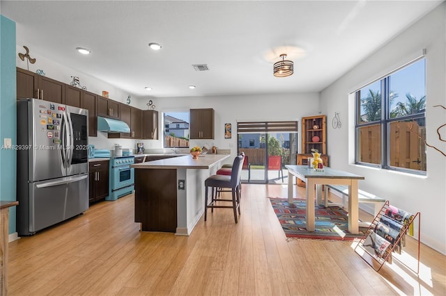25483 SW 109th Ave, Homestead, FL 33032 - kitchen with appliances with stainless steel finishes, under cabinet range hood, dark brown cabinets, a breakfast bar, and light wood-style floors