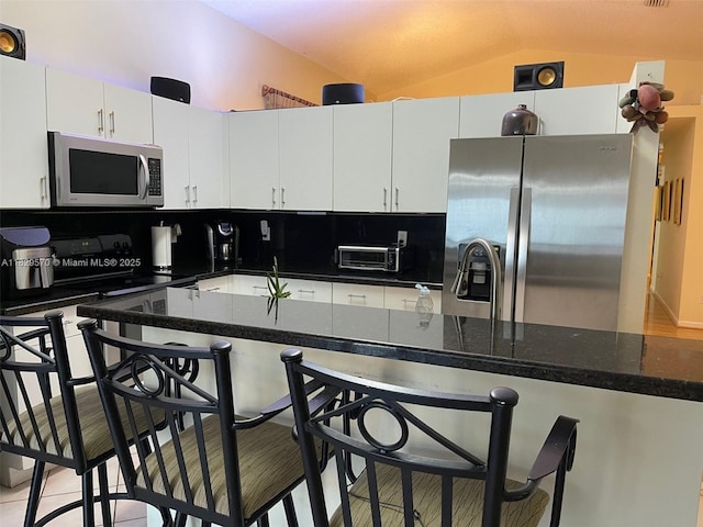 2383 SW 177th Ter, Miramar, FL 33029 - kitchen with appliances with stainless steel finishes, vaulted ceiling, a kitchen breakfast bar, white cabinets, and light tile patterned flooring