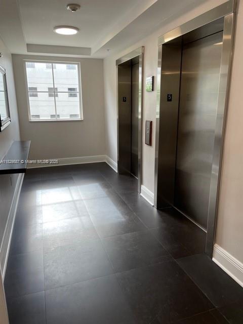 2650 SW 37th Ave Unit 501, Miami, FL 33133 - hall with elevator, dark tile patterned flooring, and a tray ceiling