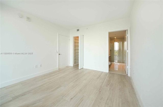 121 NE 34th St Unit 1009, Miami, FL 33137 - unfurnished bedroom with light wood-type flooring, a closet, a walk in closet, and ensuite bathroom