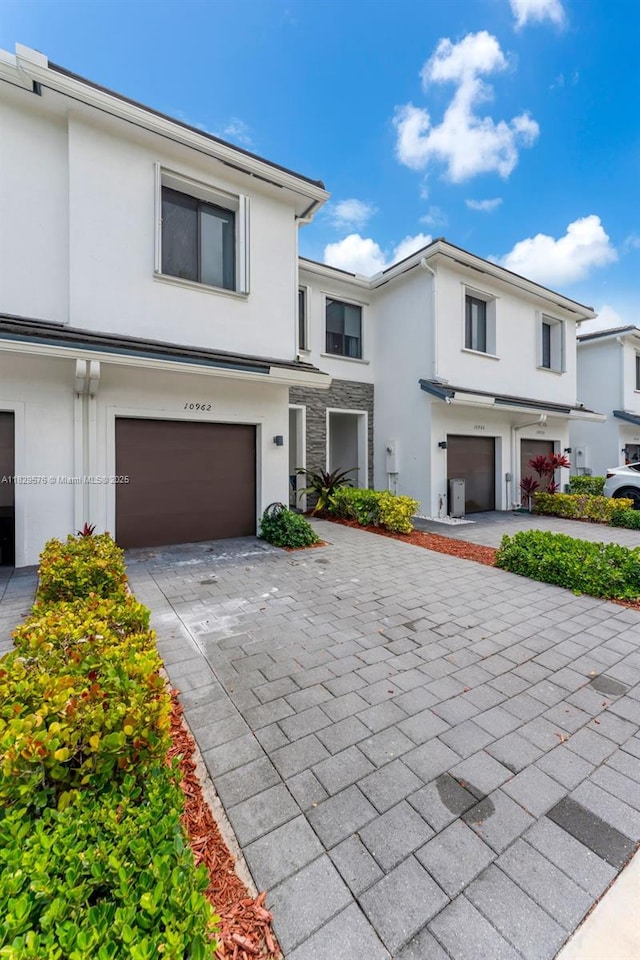 10962 SW 235, Homestead, FL 33032 - view of property featuring stucco siding, a garage, decorative driveway, and stone siding