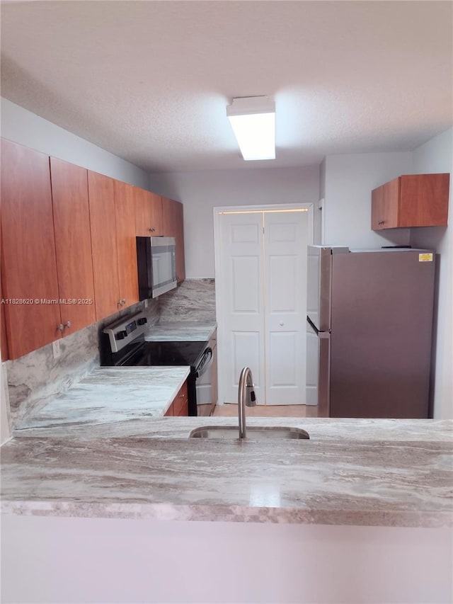 654 SW 106th Ave Unit 1502, Pembroke Pines, FL 33025 - kitchen featuring stainless steel appliances, brown cabinets, and light stone countertops