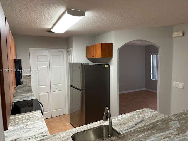 654 SW 106th Ave Unit 1502, Pembroke Pines, FL 33025 - kitchen with freestanding refrigerator, black range with electric cooktop, arched walkways, a textured ceiling, and brown cabinets