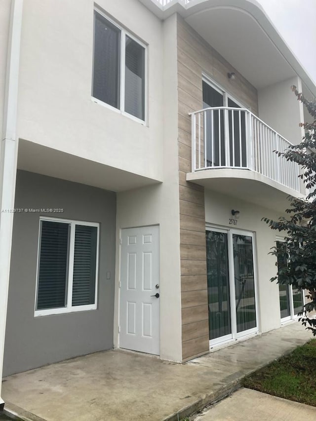 25767 SW 144th Ave, Homestead, FL 33032 - rear view of house with stucco siding, a balcony, and a patio