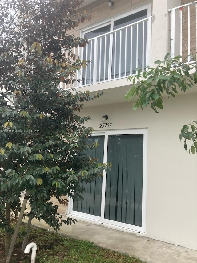 25767 SW 144th Ave, Homestead, FL 33032 - view of exterior entry featuring a balcony and stucco siding