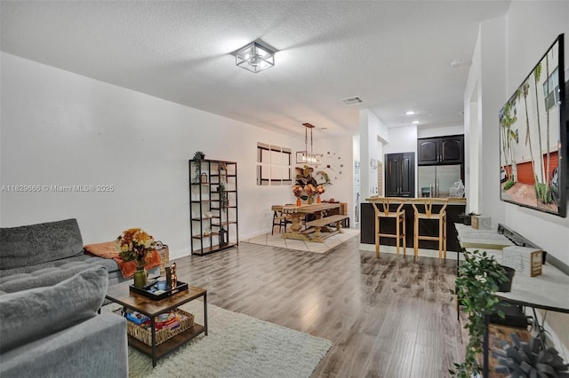 11898 SW 25th Ct Unit 103, Miramar, FL 33025 - living room with light wood-style floors, a chandelier, and a textured ceiling