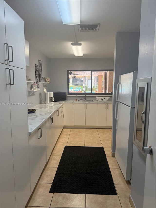 2371 SW 15th St Unit 101, Deerfield Beach, FL 33442 - kitchen with freestanding refrigerator, light tile patterned floors, white cabinets, and light stone countertops