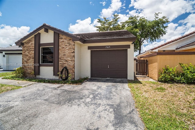 17625 NW 62nd Ct, Hialeah, FL 33015 - mid-century home with an attached garage, stucco siding, driveway, brick siding, and a tiled roof