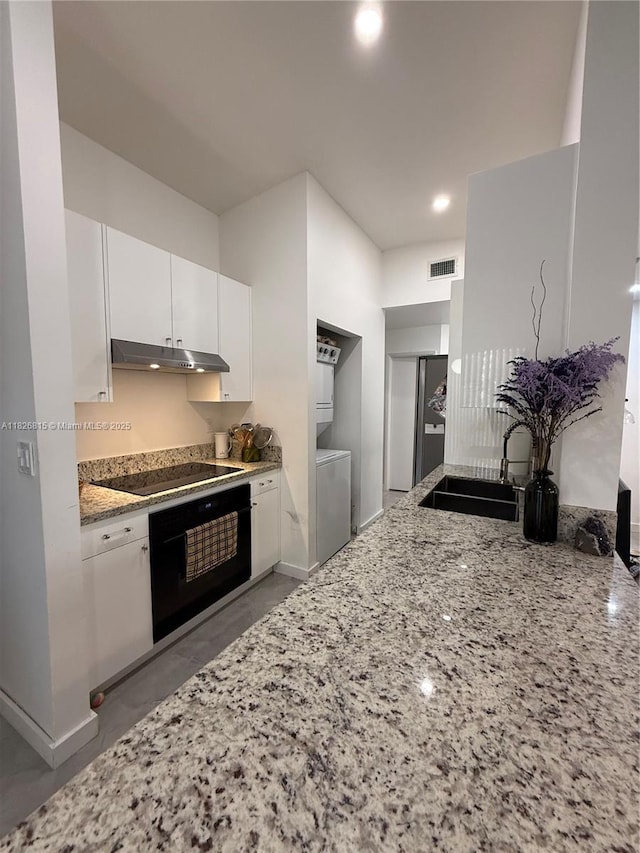 7440 SW 153rd Ct Unit 107-4, Miami, FL 33193 - kitchen with black appliances, under cabinet range hood, light stone countertops, washer / clothes dryer, and white cabinets