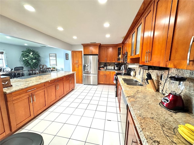 13261 SW 17th Ln, Miami, FL 33175 - kitchen with appliances with stainless steel finishes, brown cabinetry, tasteful backsplash, light stone counters, and recessed lighting