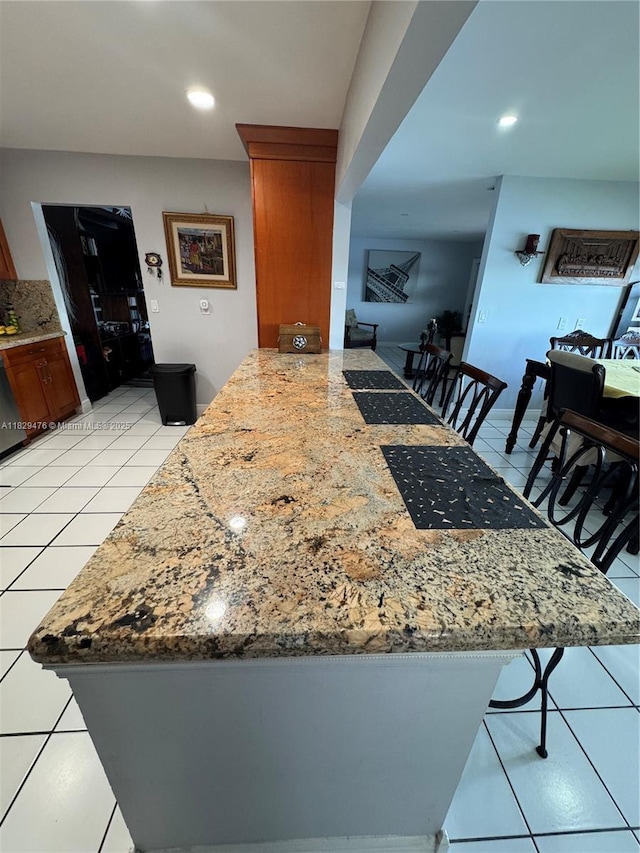 13261 SW 17th Ln, Miami, FL 33175 - kitchen featuring light tile patterned flooring, a kitchen breakfast bar, a peninsula, recessed lighting, and light stone countertops
