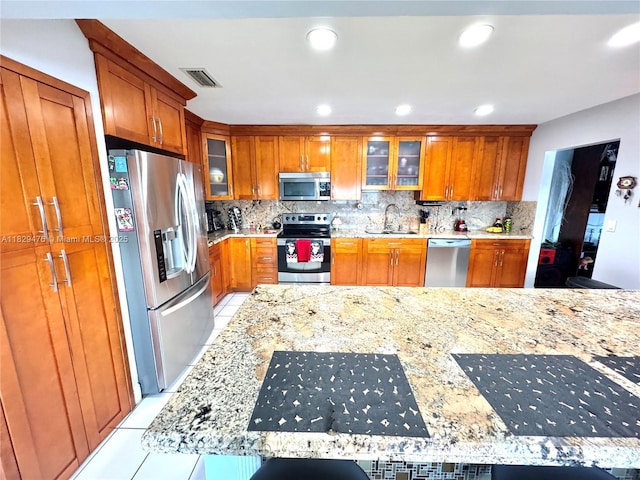 13261 SW 17th Ln, Miami, FL 33175 - kitchen with appliances with stainless steel finishes, brown cabinets, light tile patterned floors, decorative backsplash, and recessed lighting