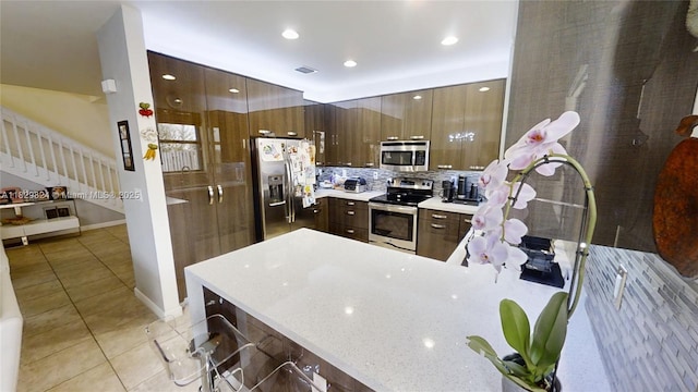 4231 SW 165th Ct, Miami, FL 33185 - kitchen featuring appliances with stainless steel finishes, light tile patterned floors, a peninsula, decorative backsplash, and a kitchen bar