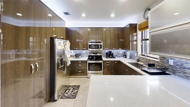 4231 SW 165th Ct, Miami, FL 33185 - kitchen with appliances with stainless steel finishes, decorative backsplash, light tile patterned floors, dark brown cabinetry, and modern cabinets