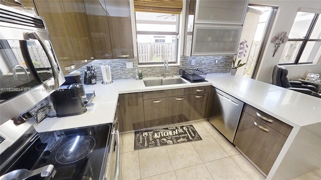 4231 SW 165th Ct, Miami, FL 33185 - kitchen featuring appliances with stainless steel finishes, a peninsula, light countertops, light tile patterned flooring, and backsplash