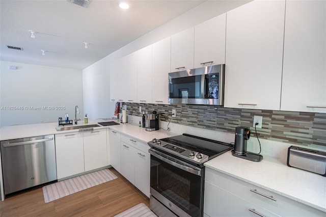 4269 NW 83rd Path, Doral, FL 33166 - kitchen with appliances with stainless steel finishes, light wood finished floors, decorative backsplash, and white cabinetry