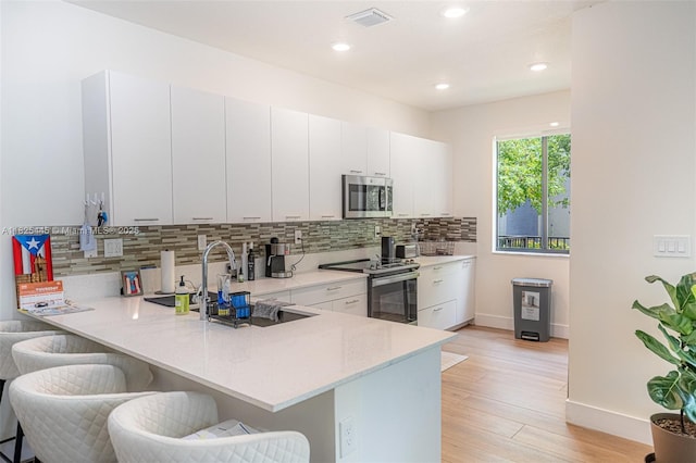 4269 NW 83rd Path, Doral, FL 33166 - kitchen featuring appliances with stainless steel finishes, a breakfast bar, backsplash, a peninsula, and light wood-style flooring