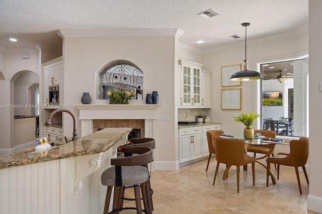 2211 Azalea Pl, Winter Park, FL 32789 - kitchen with ornamental molding, glass insert cabinets, hanging light fixtures, stone counters, and a textured ceiling