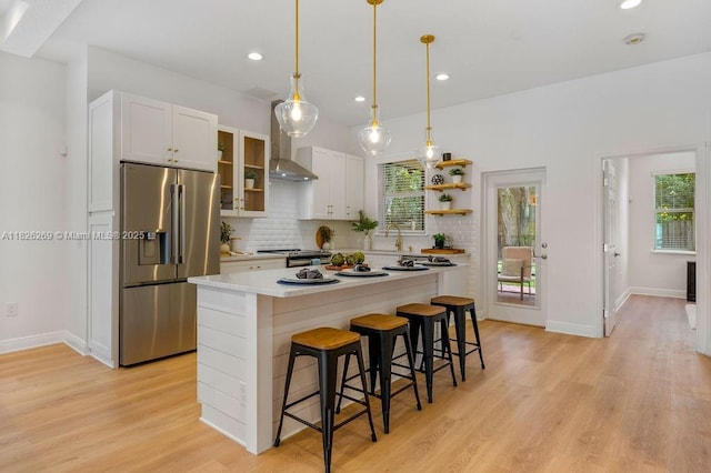 2607 Lafayette Ave, Winter Park, FL 32789 - kitchen featuring high quality fridge, wall chimney exhaust hood, a kitchen bar, light wood-type flooring, and plenty of natural light