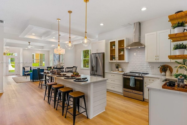 2607 Lafayette Ave, Winter Park, FL 32789 - kitchen with stainless steel appliances, wall chimney exhaust hood, white cabinetry, a breakfast bar area, and tasteful backsplash