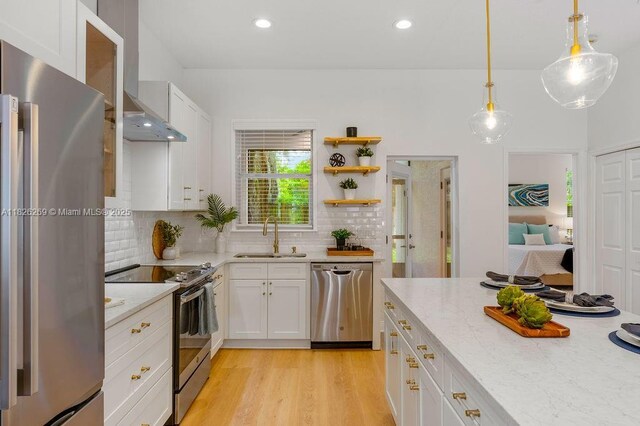 2607 Lafayette Ave, Winter Park, FL 32789 - kitchen featuring appliances with stainless steel finishes, wall chimney exhaust hood, white cabinetry, tasteful backsplash, and light stone counters