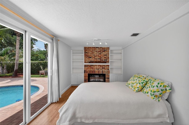 6201 SW 3rd St, Plantation, FL 33317 - bedroom with access to exterior, wood finished floors, a textured ceiling, and a fireplace