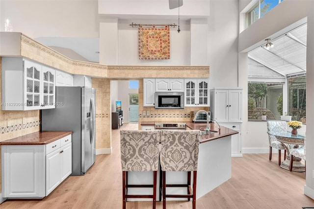 321 NW 100th Ave, Plantation, FL 33324 - kitchen featuring appliances with stainless steel finishes, glass insert cabinets, decorative backsplash, and a high ceiling